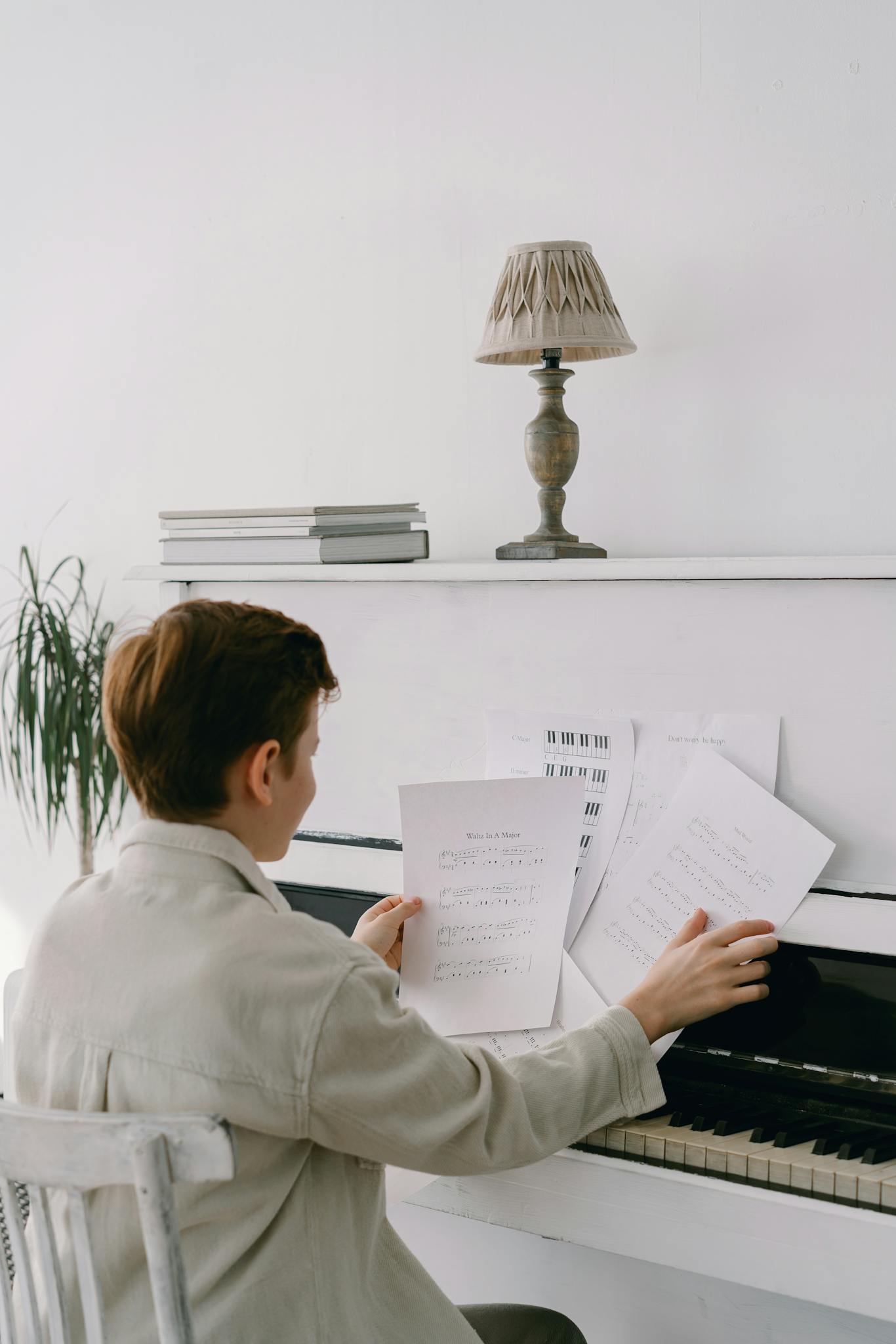 A young boy organizes sheet music while sitting at a piano, indicating his passion for music.
